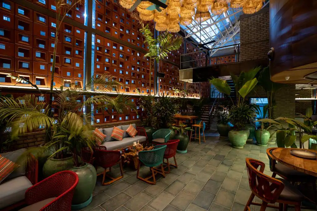 Photograph from Makau's own venue gallery: the double-height atrium, terracotta jaali and hanging raffia birds overhead.