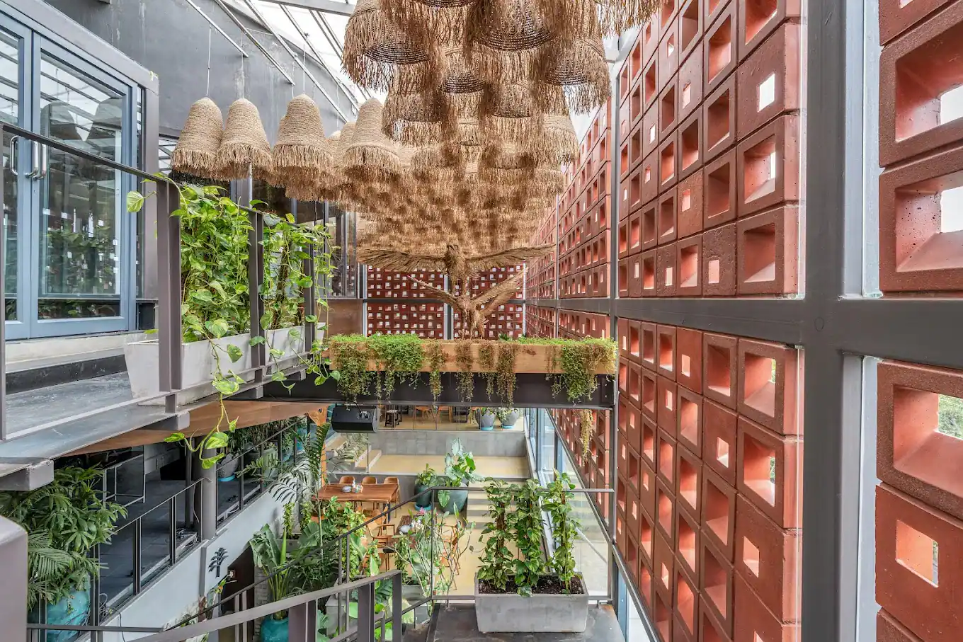 Photograph from Makau's own venue gallery: the double-height atrium, terracotta jaali and hanging raffia birds overhead.