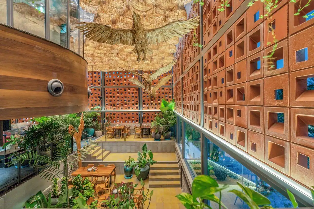 Photograph from Makau's own venue gallery: the double-height atrium, terracotta jaali and hanging raffia birds overhead.