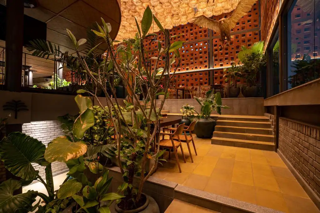 Photograph from Makau's own venue gallery: the double-height atrium, terracotta jaali and hanging raffia birds overhead.