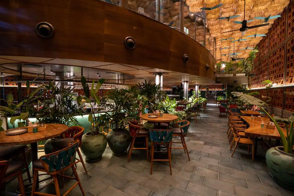Photograph from Makau's own venue gallery: the double-height atrium, terracotta jaali and hanging raffia birds overhead.
