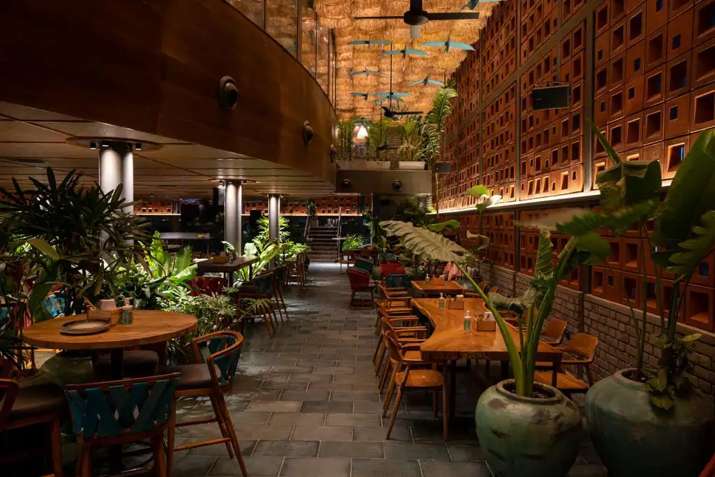 Photograph from Makau's own venue gallery: the double-height atrium, terracotta jaali and hanging raffia birds overhead.